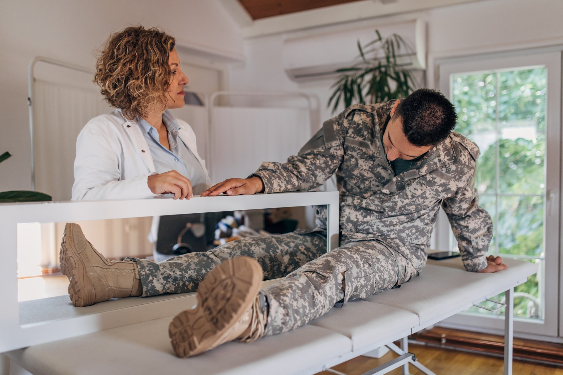 Doctor Helping Military Veteran Amputee Alleviate Phantom Pain Through Mirror Therapy